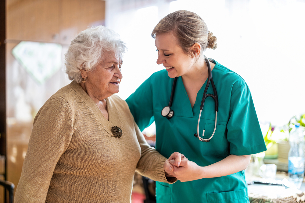 A caregiver gently holding the hands of an elderly resident at Country Gardens